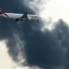 យន្តហោះ Boeing 777 របស់ Emirates កំពុងរៀបចំចុះចត ខណៈដែលផ្សែងហុយចេញពីអគ្គីភ័យដែលកំពុងបន្តនៅអាកាសយានដ្ឋានអន្តរជាតិឌូបៃ ក្នុងទីក្រុងឌូបៃ នៅថ្ងៃទី១៦ ខែមីនា ឆ្នាំ២០២៦ [ឯកសារ៖ AFP]