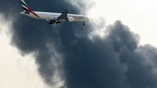 យន្តហោះ Boeing 777 របស់ Emirates កំពុងរៀបចំចុះចត ខណៈដែលផ្សែងហុយចេញពីអគ្គីភ័យដែលកំពុងបន្តនៅអាកាសយានដ្ឋានអន្តរជាតិឌូបៃ ក្នុងទីក្រុងឌូបៃ នៅថ្ងៃទី១៦ ខែមីនា ឆ្នាំ២០២៦ [ឯកសារ៖ AFP]